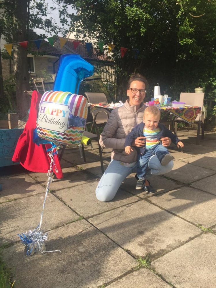 a photo of a woman and child on a patio next to birthday balloons
