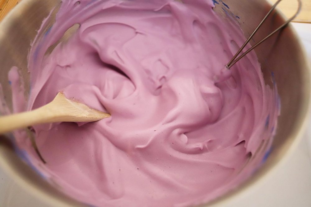 a photo of purple foam and a wooden spoon in it.