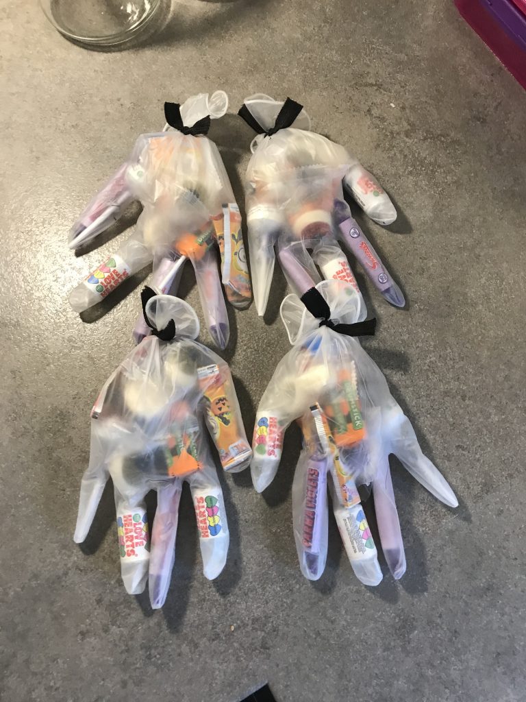 A photo of 4 white/see through gloves with sweets inside