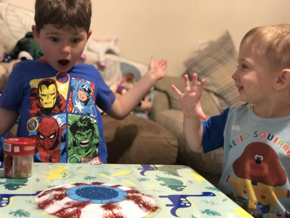 2 boys looking amazed at their craft- a monster eye paper plate