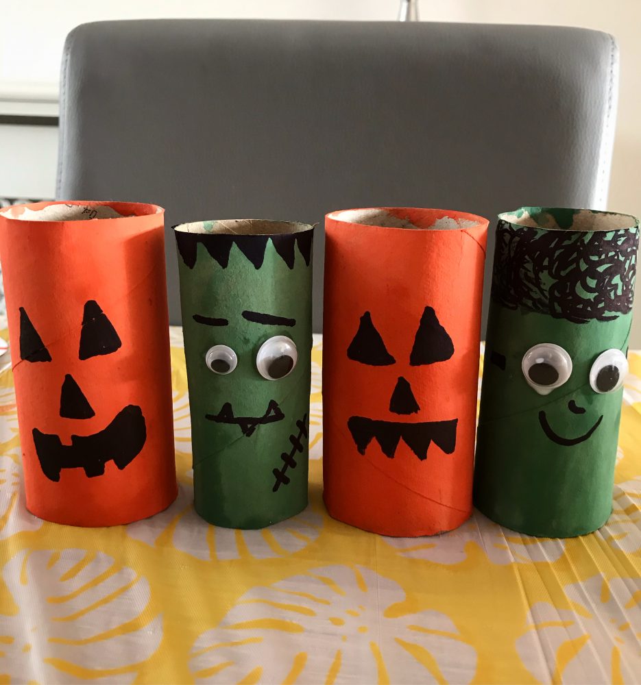 A photo of 4 toilet rolls, 2 painted orange with pimpkin faces on and 2 painted green with googly eyes on - to look like frankensteins monster