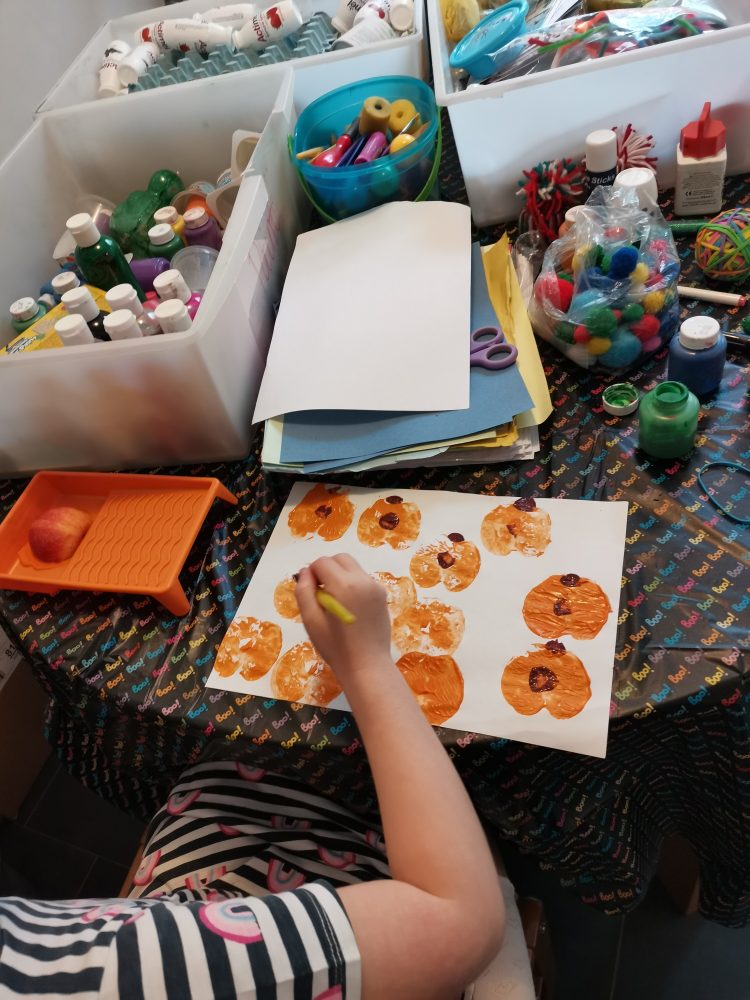 A photo of a girl painting orange pumpkins on paper