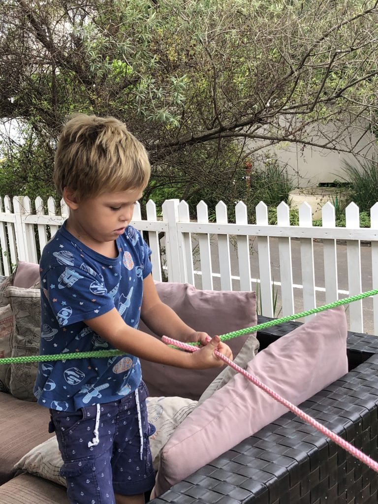 a photo of a boy holding a pink and green rope that are being tied together