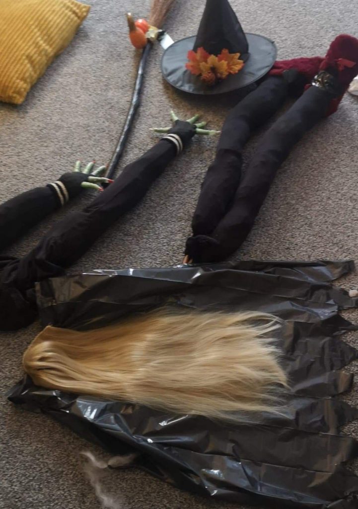 a photo of parts of a witch - hair, hat, broom, arms and legs on the floor