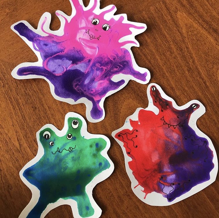 a photo of 3 colourful monster pictures on a table 