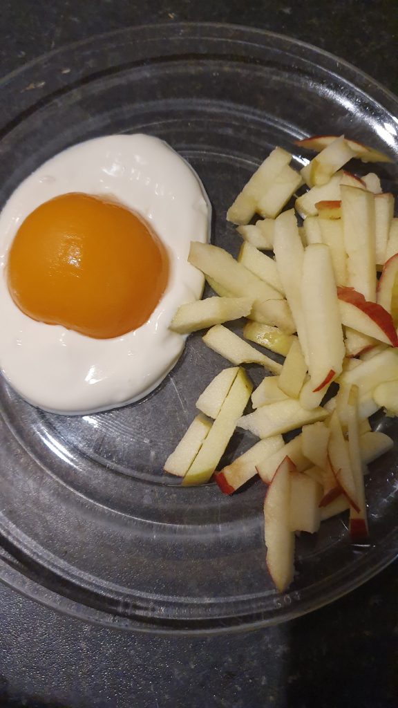 A photo of "eggs and chips" made from  a peach, yogurt and apple slices