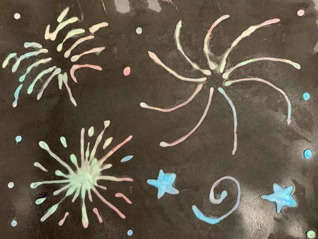 A photo of black paper with firework designs on
